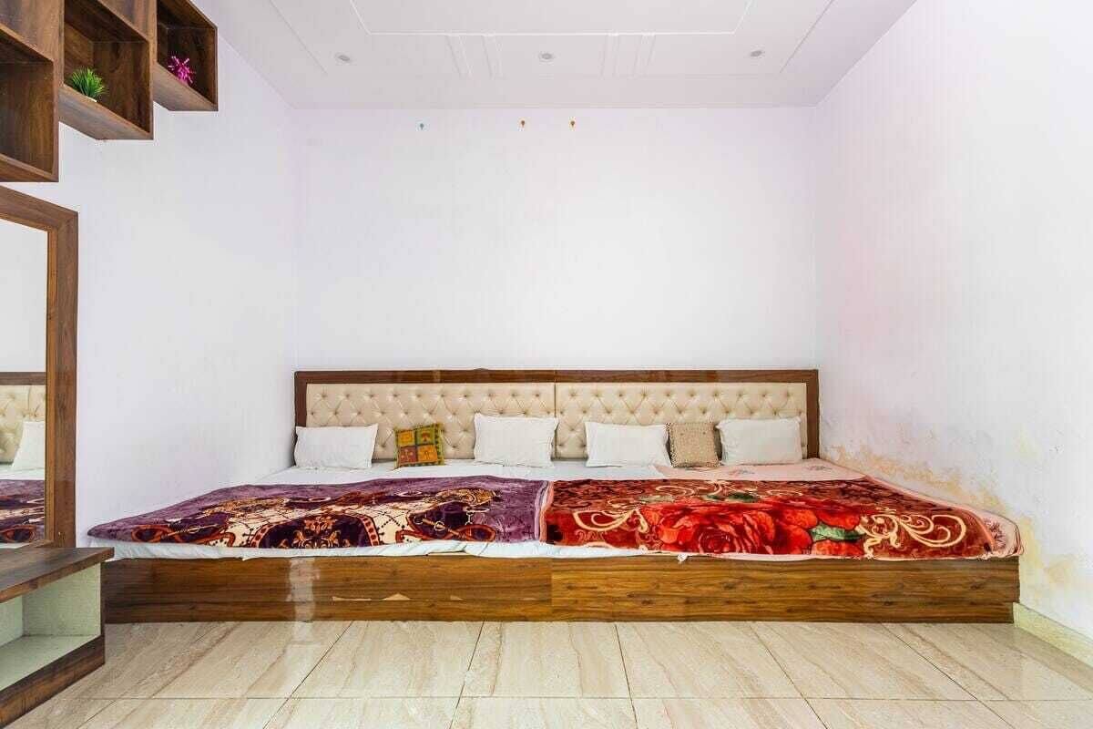 Une chambre avec un grand lit, une tête de lit en bois et un miroir sur le côté gauche.