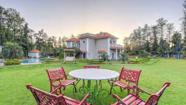A large house with a swimming pool, surrounded by a well-maintained lawn and trees. - ARAVALI HILLS RESORT  (Sohna)