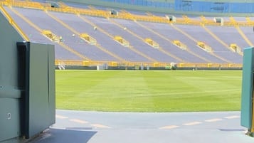 An empty stadium with tiered seating and a green field.