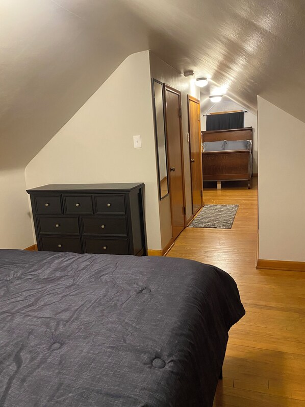 Un dormitorio con cama, cómoda y suelo de madera.