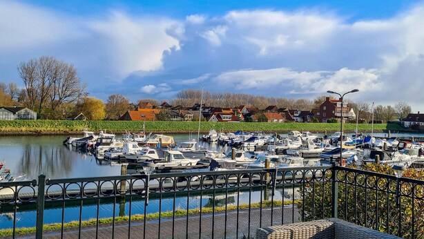 A marina with boats docked along a riverbank, surrounded by residential buildings and a clear sky. - 3 bedroom nice home in Stavenisse (Stavenisse)