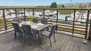 A covered outdoor dining area with a table and chairs, overlooking a marina with boats. - 3 bedroom nice home in Stavenisse (Stavenisse)