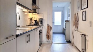 A narrow kitchen with white cabinets, a stove, and a coffee maker. There is a door leading to another room. - 3 bedroom nice home in Stavenisse (Stavenisse)