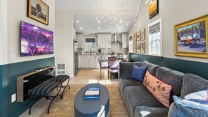 Una sala de estar moderna con un sofá gris, una mesa de centro y un televisor montado en la pared.