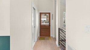 Un pasillo con puerta de madera, un radiador y una ventana.