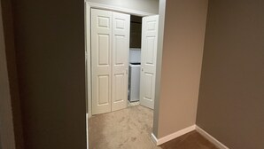 A hallway with beige carpet, white double doors, and a ceiling light.