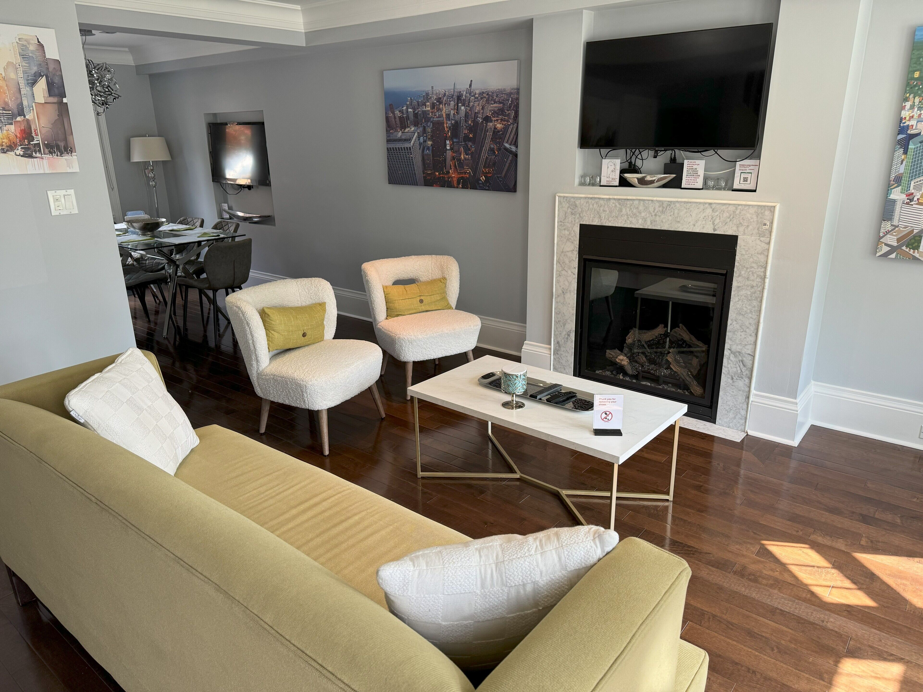 Una sala de estar con un sofá, dos sillones, una mesa de centro, una chimenea y un televisor.