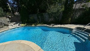 A swimming pool with clear blue water, surrounded by a stone deck and a wooden fence. - Leaside Rental w/ Backyard& Pool, 3-bedroom house in fantastic Toronto (Toronto)