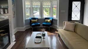 A living room with a fireplace, two blue armchairs, a beige sofa, and a coffee table. - Leaside Rental w/ Backyard& Pool, 3-bedroom house in fantastic Toronto (Toronto)