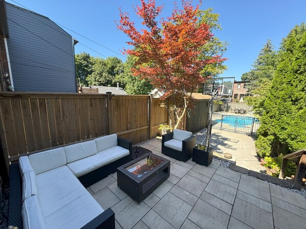 A backyard patio with a sofa, two chairs, and a coffee table.