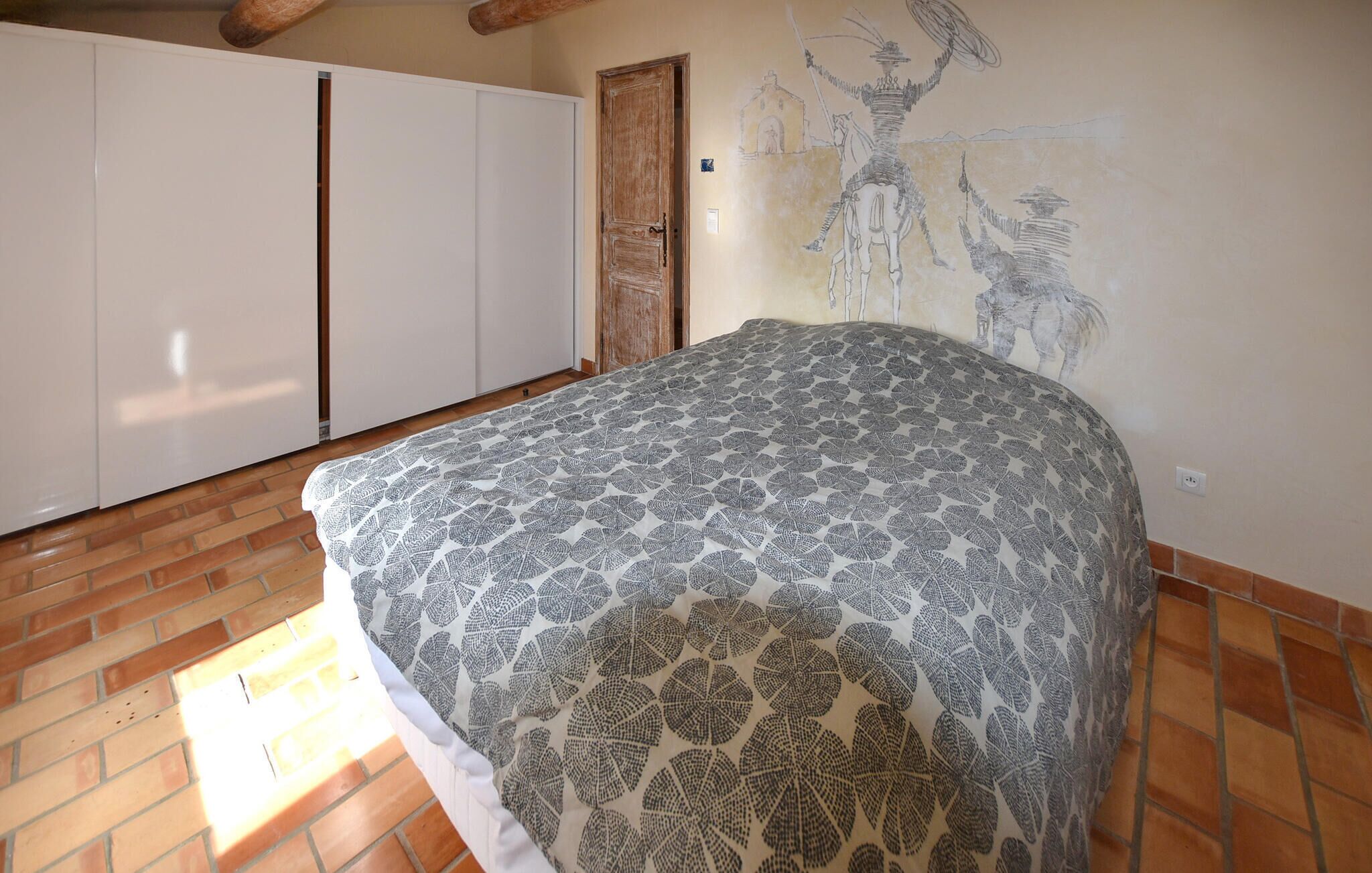 A bedroom with a bed, a wardrobe, and a mural on the wall.