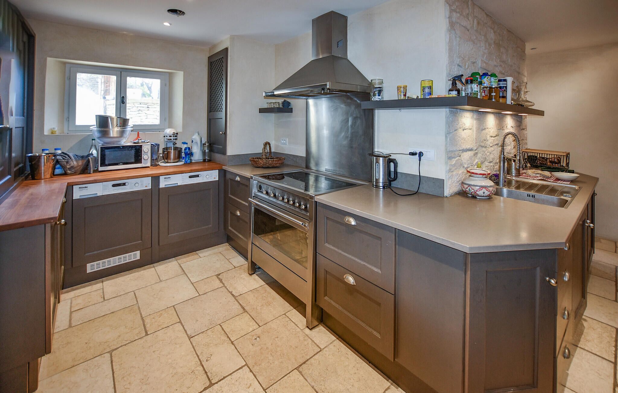 A modern kitchen with a built-in oven, microwave, and stainless steel range hood.