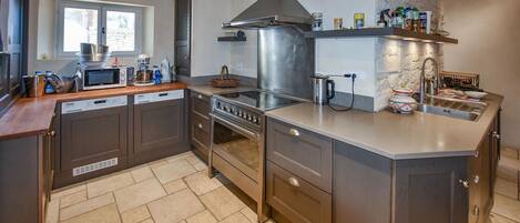 A modern kitchen with a built-in oven, microwave, and stainless steel range hood.