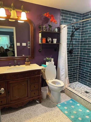 Een badkamer met een wastafel, toilet, douche en decoratieve items.