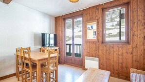 A wooden-paneled room with a dining table, chairs, a television, and a bed. - Apartment in Saint-Sorlin near Ski Resort (Saint-Sorlin-d´Arves)
