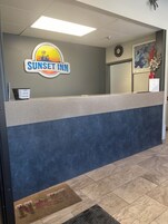 Una mesa de recepción en el Sunset Inn, con un reloj y un cuadro en la pared.