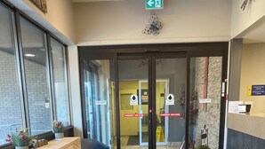 A reception area with a check-in counter, seating area, and a door with emergency instructions. - Sunset Inn Kenora (Kenora)