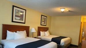A hotel room with two beds, a desk, and a chair. - Sunset Inn Kenora (Kenora)