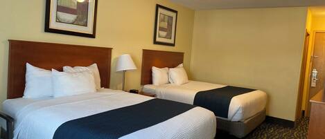 Ein Hotelzimmer mit zwei Betten, einem Schreibtisch und einem Stuhl.