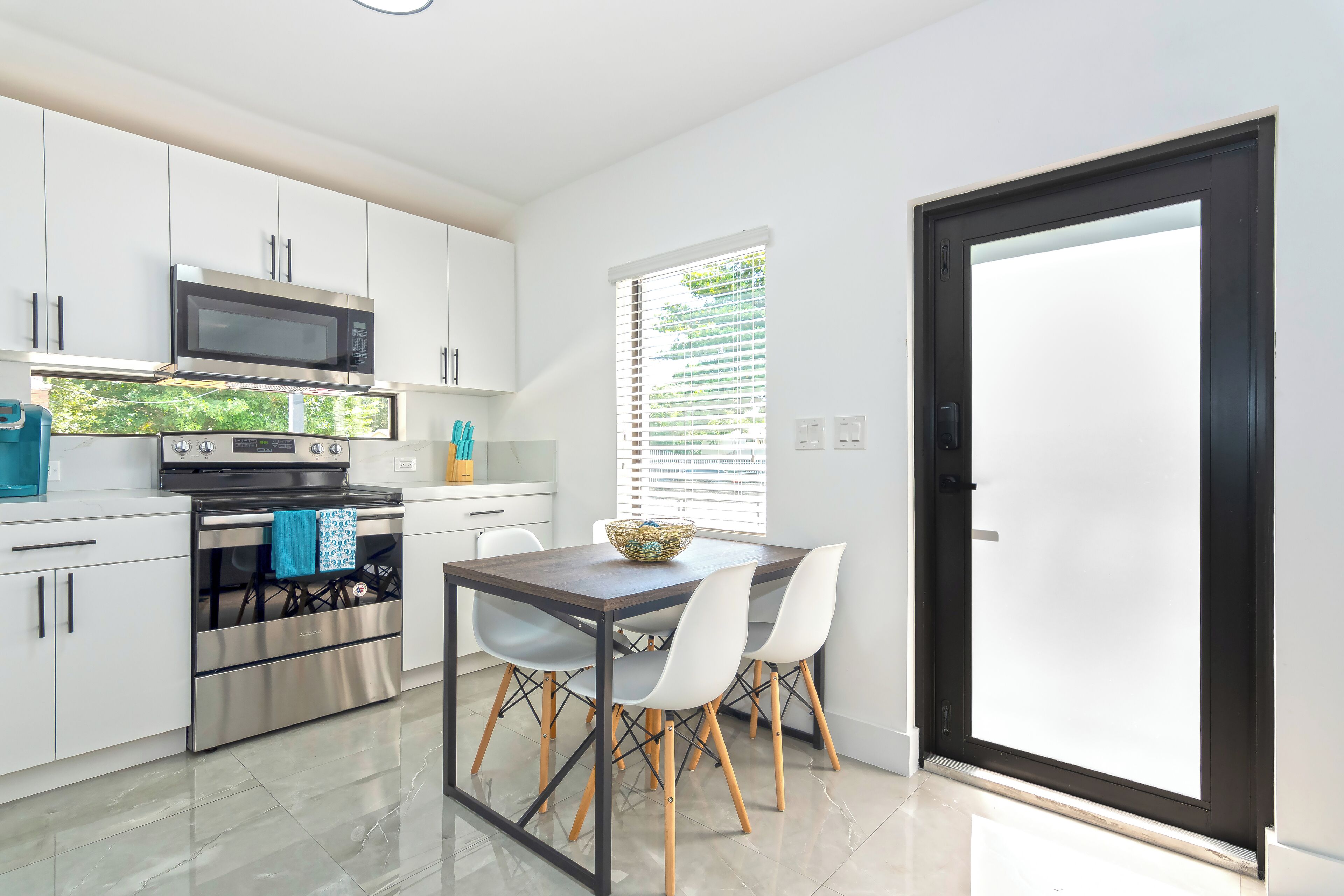 A modern kitchen with white cabinets, a stainless steel oven, and a dining table with chairs.
