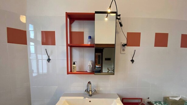 A bathroom with a white sink, a mirror, and a shelf with toiletries. - Spacious manor house apartment near the Saale and Elbe rivers (Calbe (Saale))