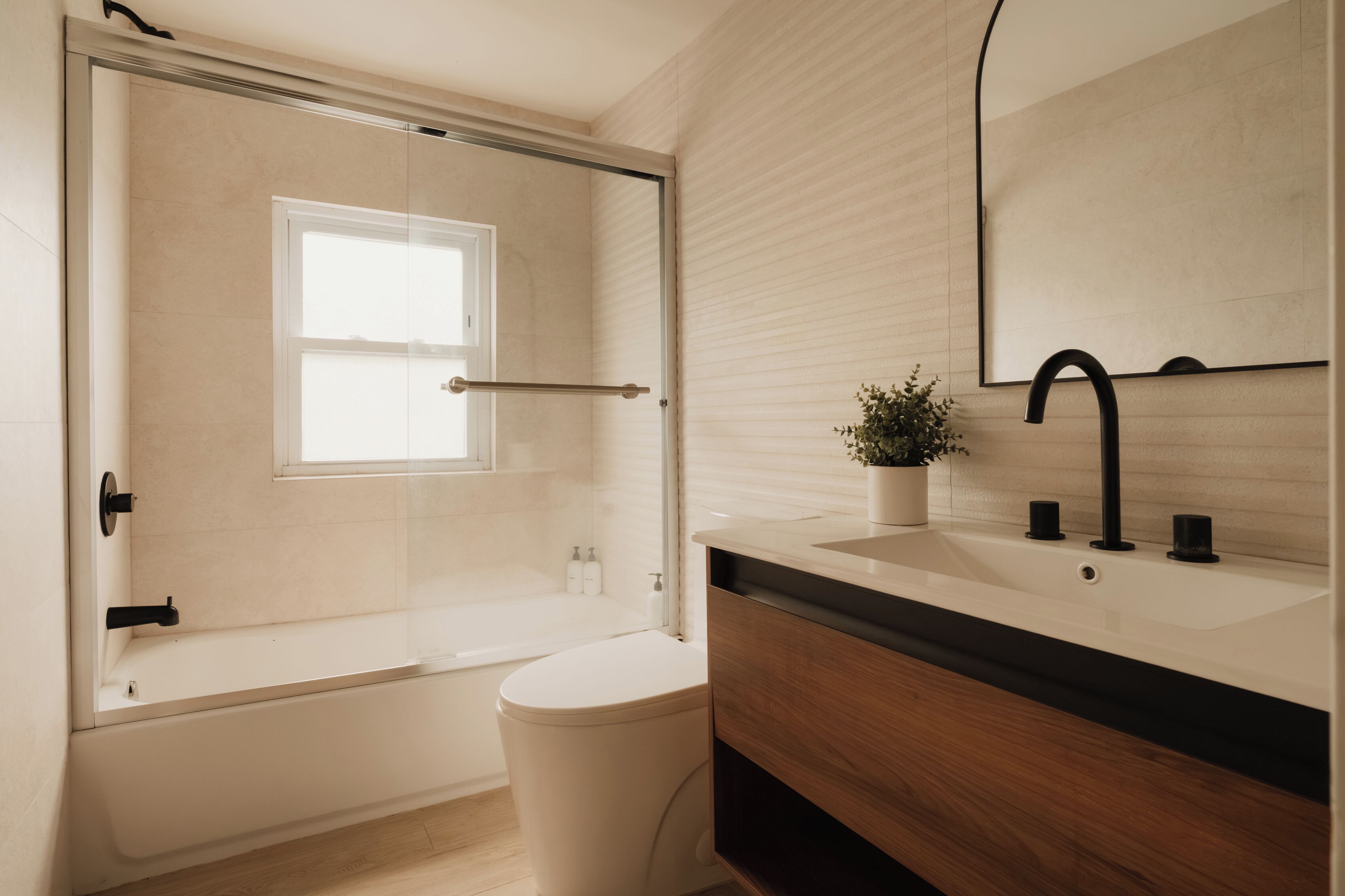 A modern bathroom with a bathtub, toilet, and sink.