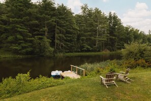A lakeside setting with a dock, two chairs, and a rowboat. - Great Lodge at Carter Bridge Estate (East Durham)