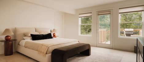 A bedroom with a bed, bedside lamps, a bench, and large windows.