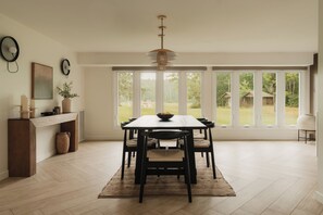 A dining area with a large table, chairs, a rug, and a view of the outdoors through large windows. - Great Lodge at Carter Bridge Estate (East Durham)
