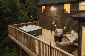 A deck with a hot tub, outdoor furniture, and string lights. - Great Lodge at Carter Bridge Estate (East Durham)
