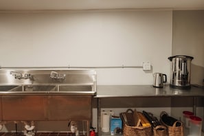 Una cocina con electrodomésticos de acero inoxidable, un fregadero y una estantería con cestas y un hervidor.