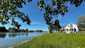 A serene lakeside view with a white house and lush greenery. - Stunning Chesapeake Waterfront Home (Oxford)