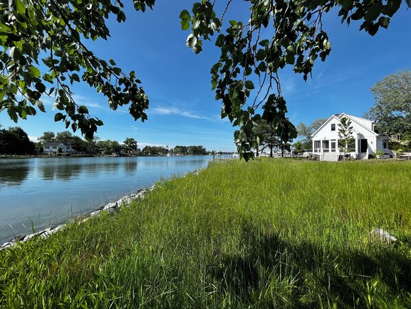Une vue paisible sur un lac, avec une maison blanche et une végétation luxuriante.