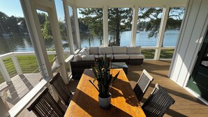 A covered outdoor dining area with a large wooden table, chairs, and a potted plant. - Stunning Chesapeake Waterfront Home (Oxford)