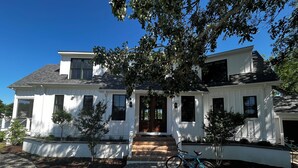 A two-story white house with a front porch, a bicycle parked in front, and a driveway with gravel. - Stunning Chesapeake Waterfront Home (Oxford)