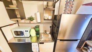 A compact kitchen with a microwave, kettle, and sink.