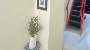 A staircase with red handrails, a wall-mounted light fixture, a framed picture, and a potted plant.