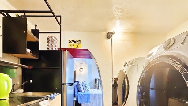 A compact laundry room with two washing machines, a small kitchenette, and a caution sign.