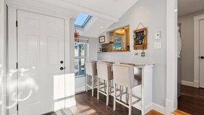 A modern kitchen with a bar area, white cabinetry, and a skylight.