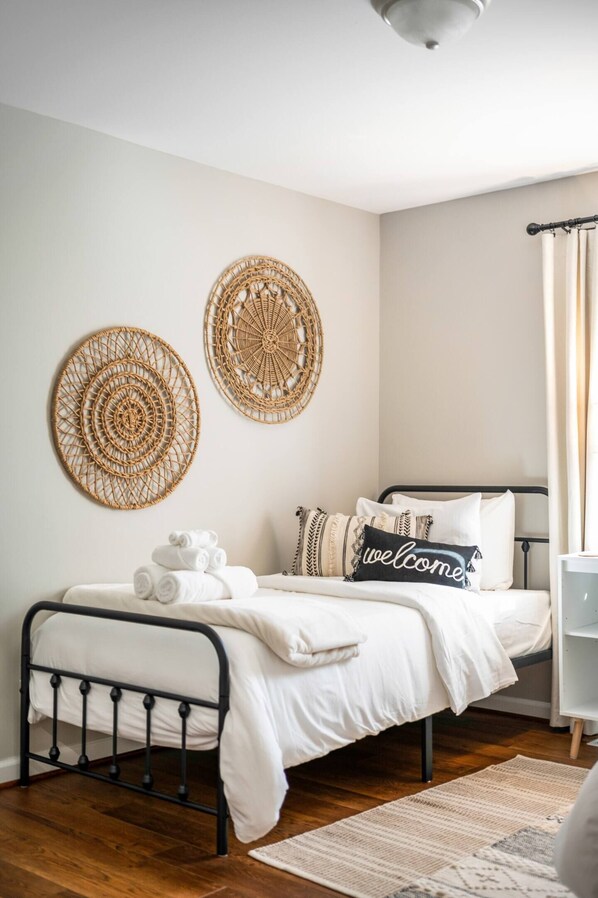 A neatly arranged bedroom with a bed, a bedside table, and two wall-mounted decorative items. - Lg Yard/Deck/2 Living Rooms/Home away from home/Everything you need/Comfy Beds (Lynchburg)
