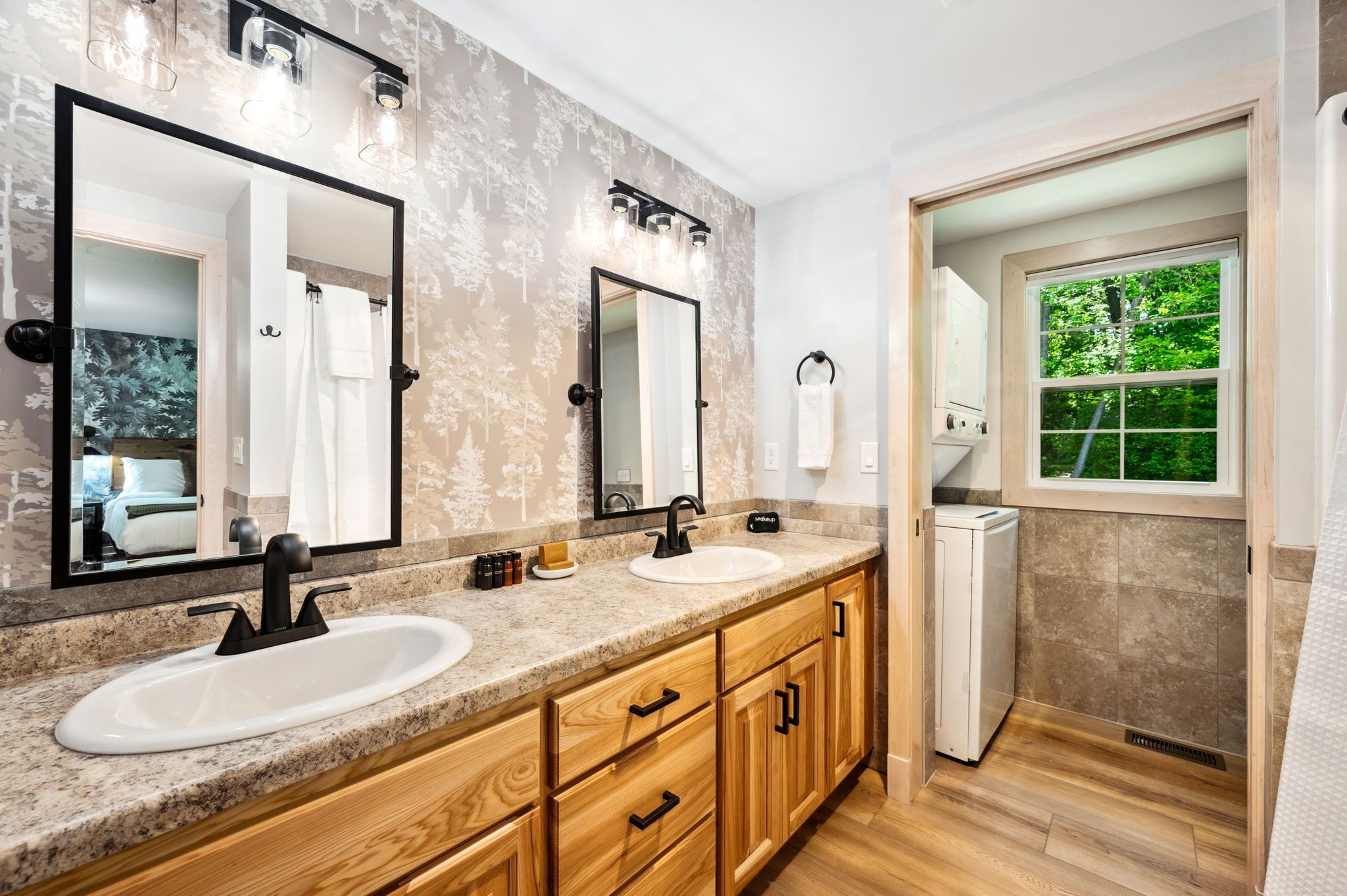 A modern bathroom with two sinks, wooden cabinets, and a large mirror.