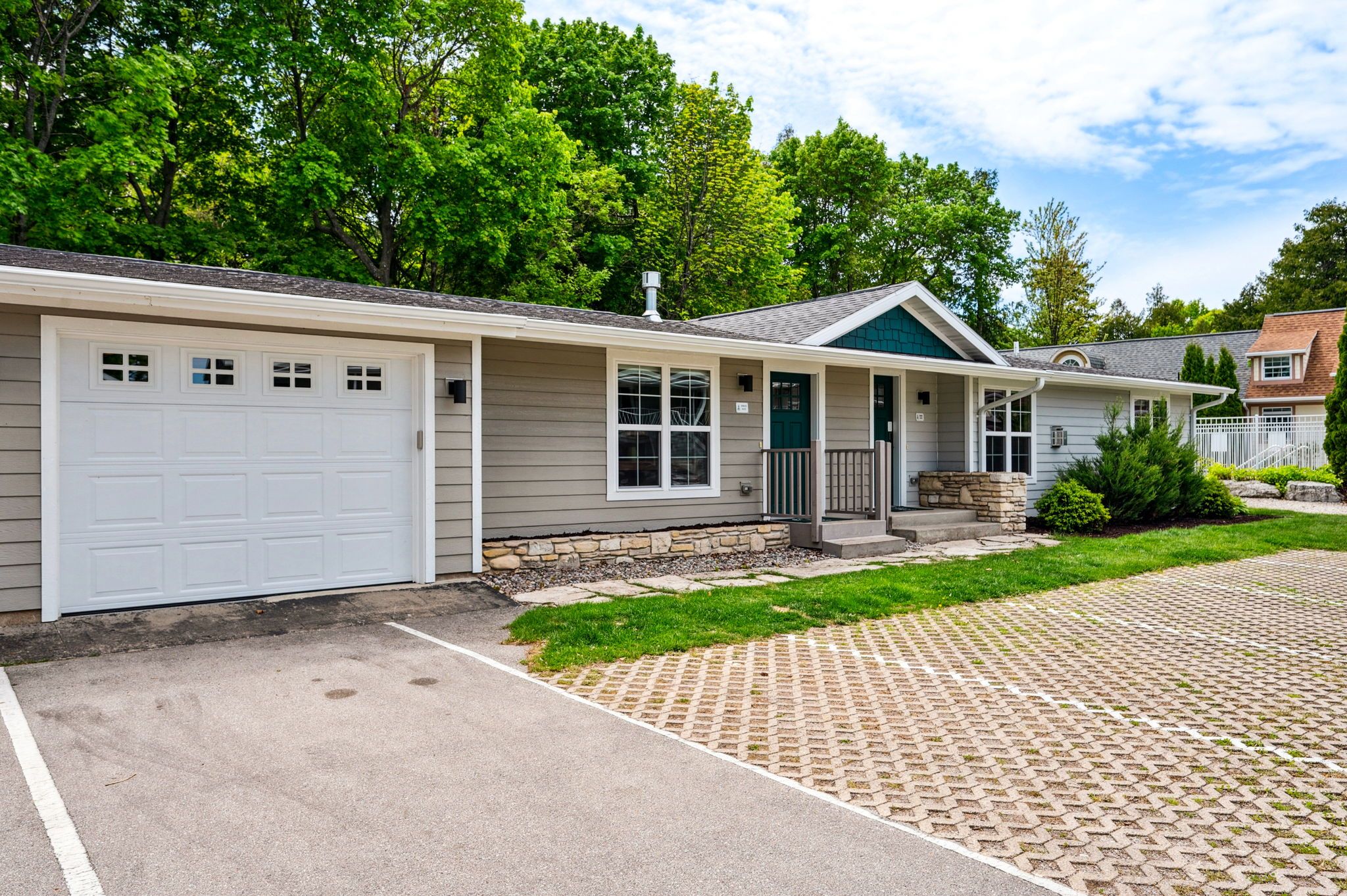 Une maison de plain-pied avec un garage, un porche à l’avant et une allée pavée.