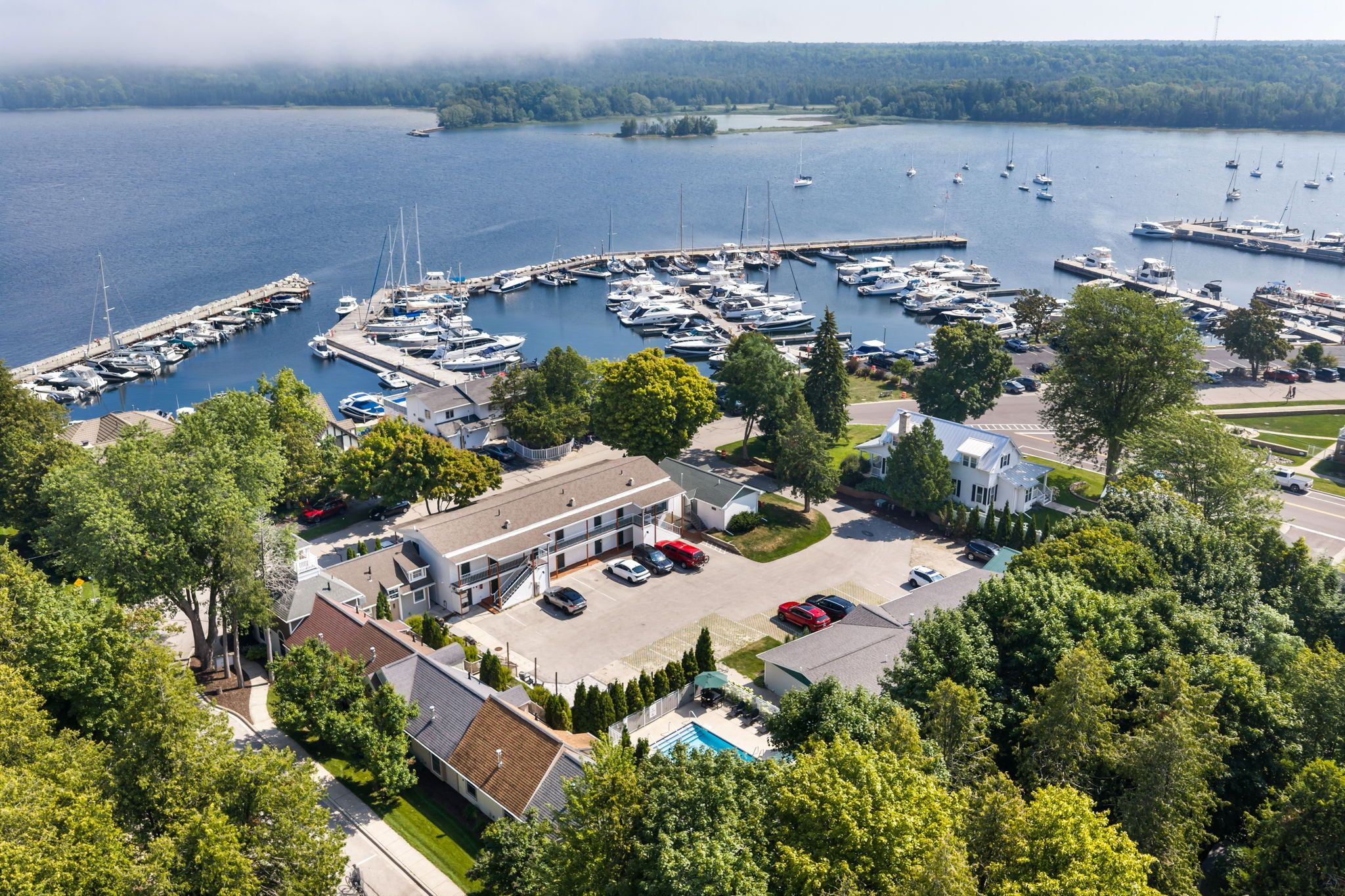 A marina with multiple boats docked, surrounded by lush greenery and residential buildings.