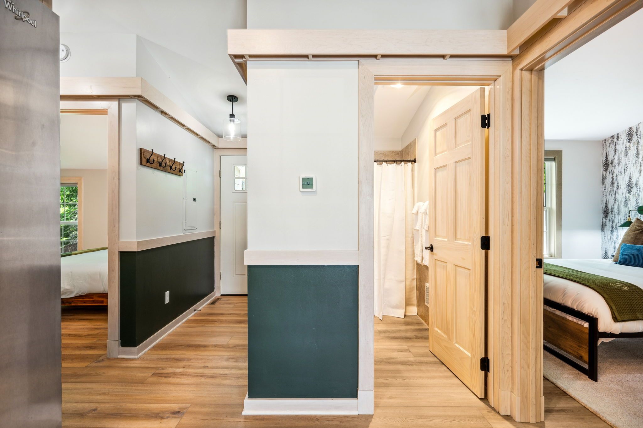A hallway with a bed, a wardrobe, and a door leading to another room.