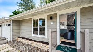 A motel with a covered porch, stone foundation, and a welcome mat. - Spruce Suite | Downtown Fish Creek~Dog-friendly (Fish Creek)