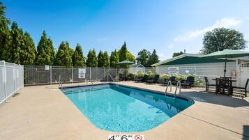 A rectangular pool with a no diving sign at the bottom, surrounded by a white fence, and a patio area with outdoor furniture.