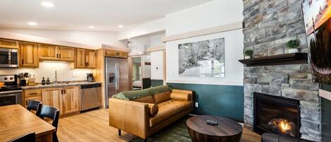 A modern kitchen with wooden cabinets, stainless steel appliances, and a dining area with a wooden table and chairs.