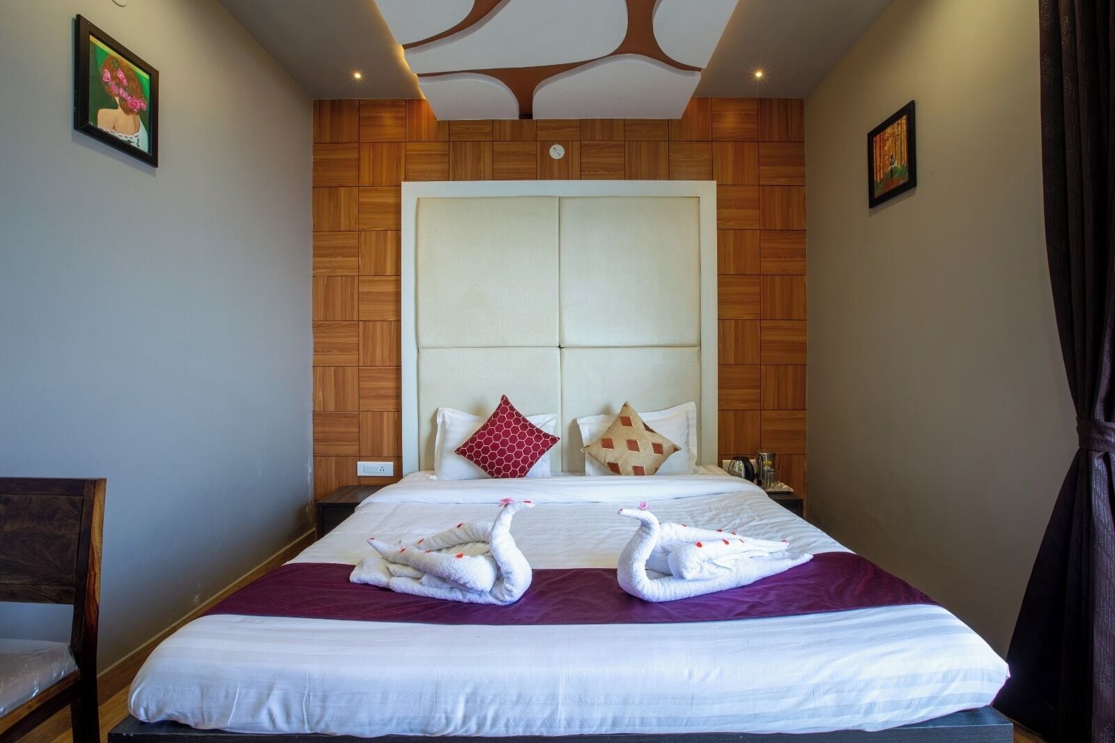 A hotel room with a large bed, wooden panel wall, and two swan-shaped pillows.