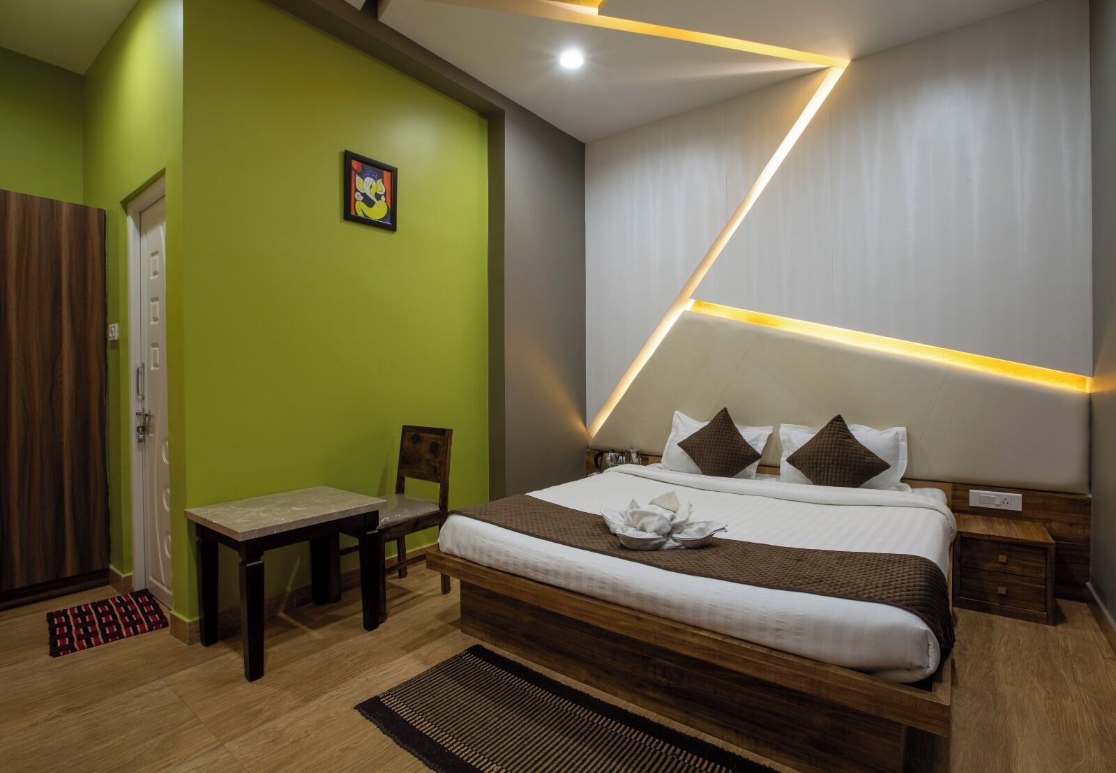 A modern hotel room with a large bed, a small table, a chair, and a door.