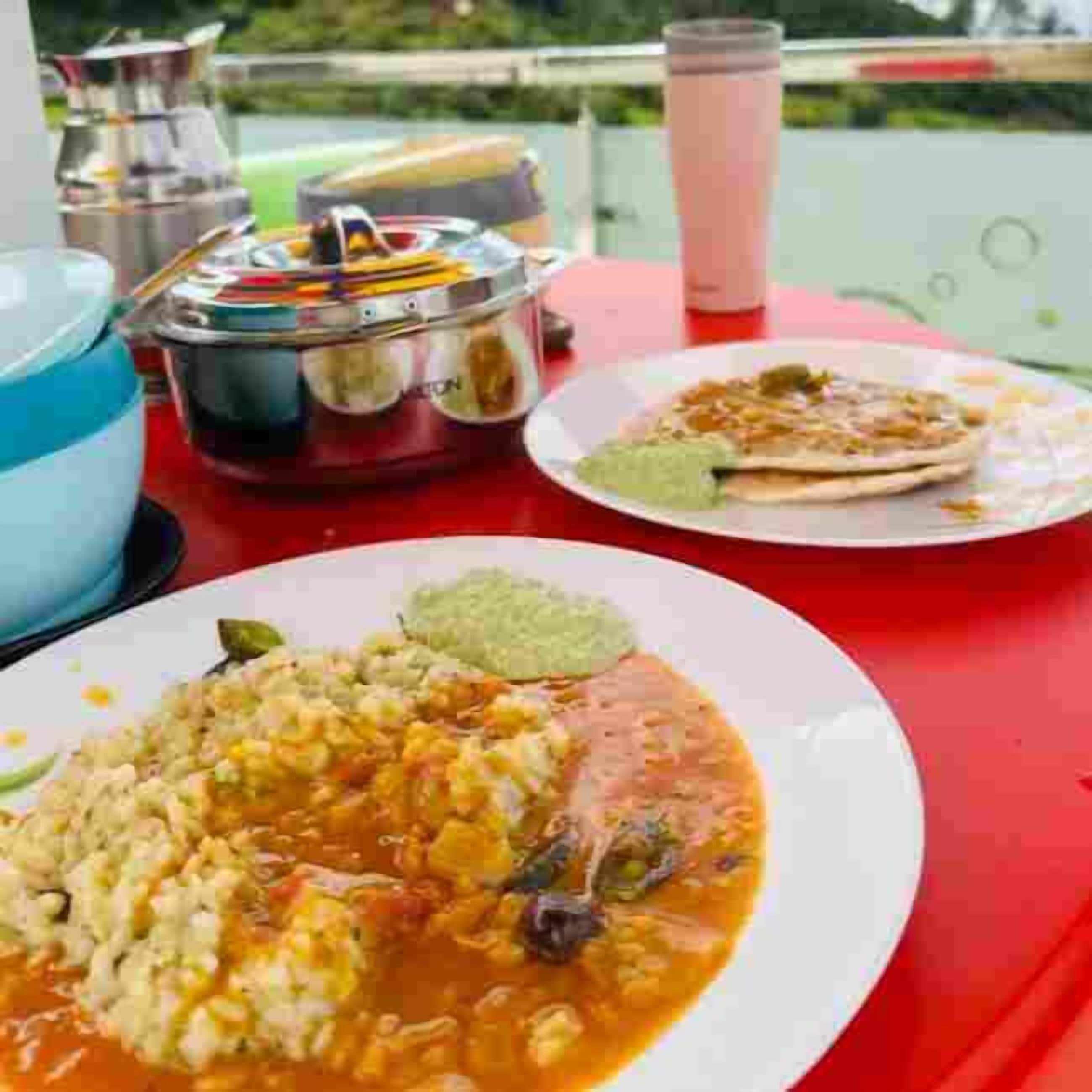 A dining table with a plate of food, a thermos, and a container.